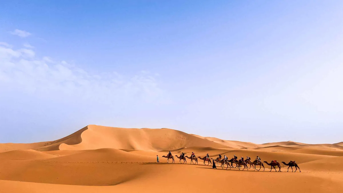 Camel caravan crossing the Erg Chebbi dunes at sunrise on a 3-day Merzouga desert tour from Marrakech